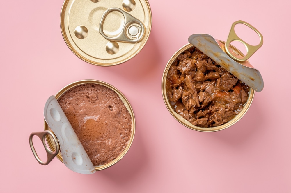 Wet Cat Food In Open Jars Over Pastel Pink Background